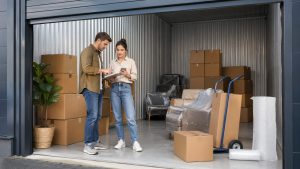 Couple organisant des cartons et des meubles protégés dans un box avant déménagement pour gagner du temps et limiter les frais